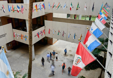 Flags flutter in a courtyard while students walk below