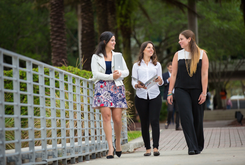 Three female graduate students walking and talking through campus.