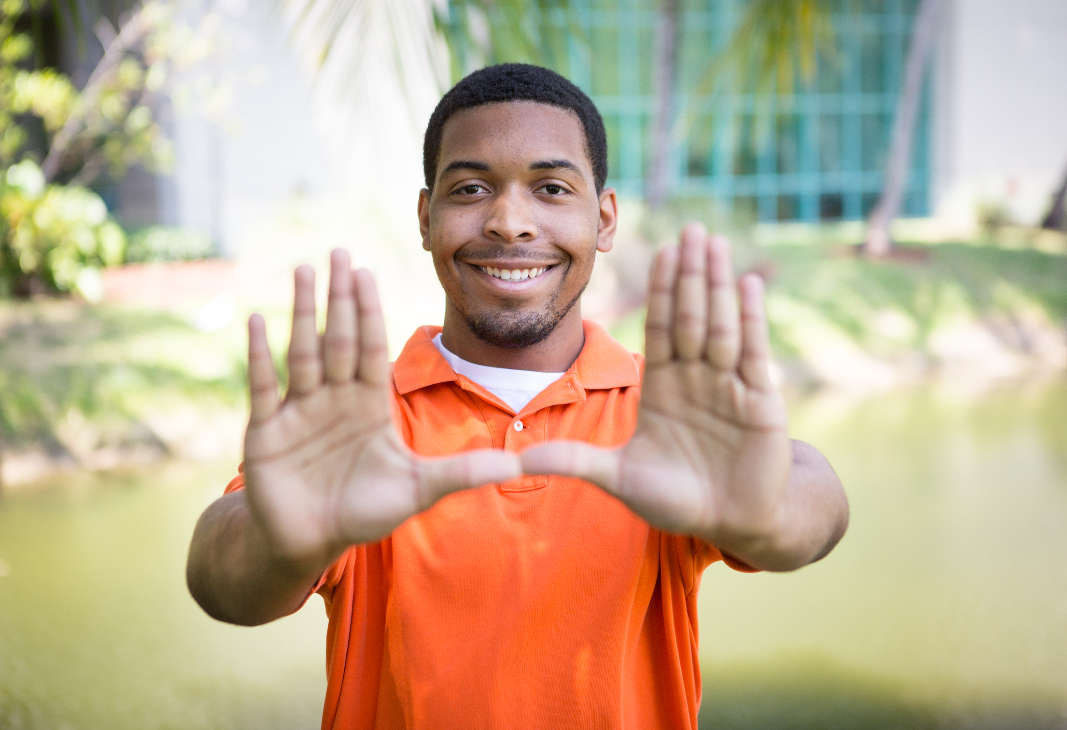 Close-up of male student outdoors holding up the U sign with his hands.