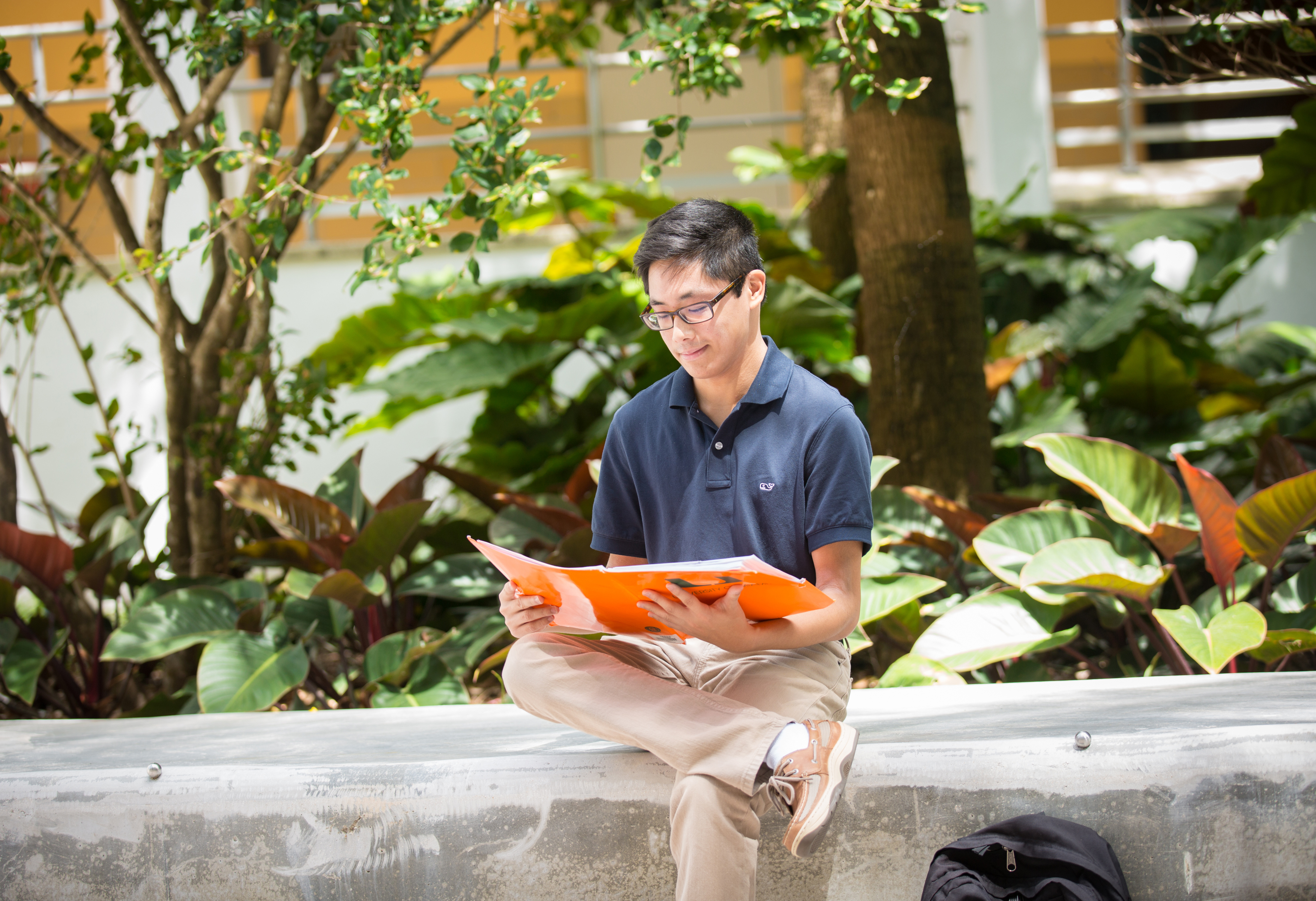  Student sitting and reading outdoors.
