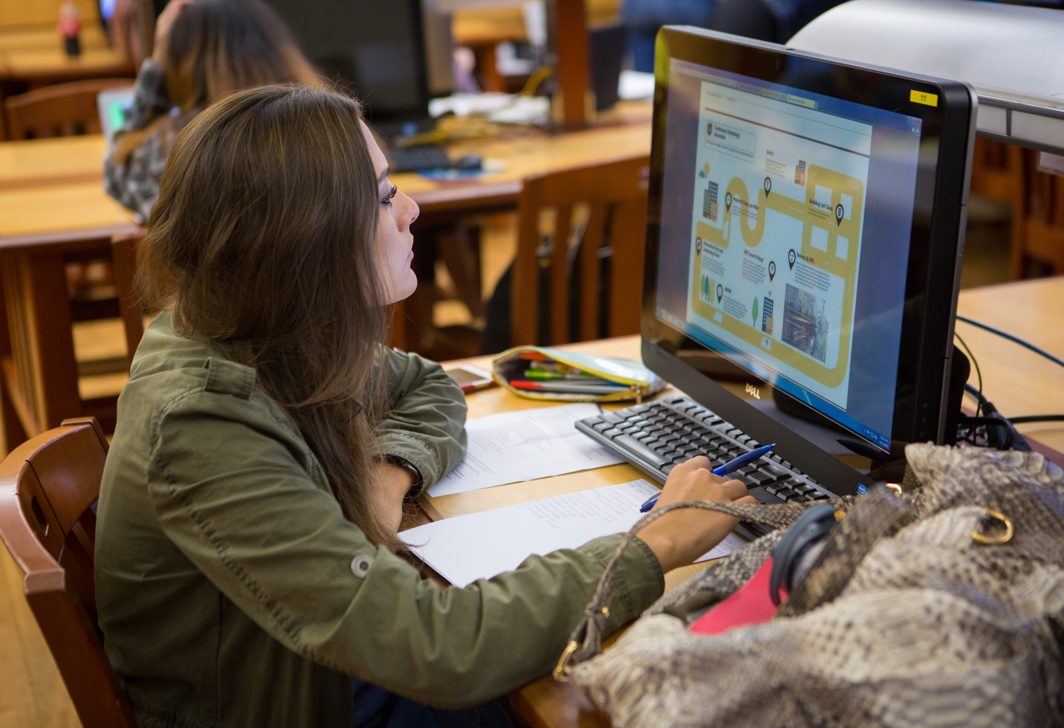 Female student sitting in the library in front of a computer.