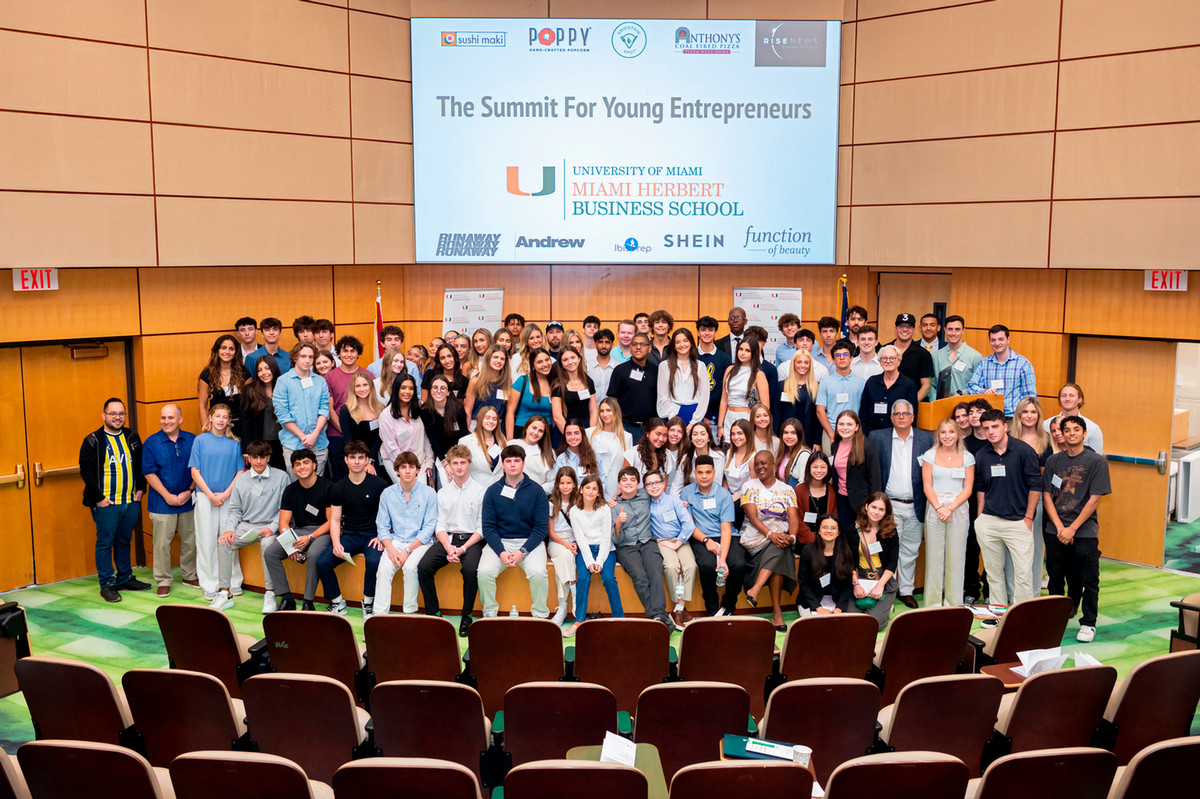 Group of students and faculty smiling at camera in auditorium